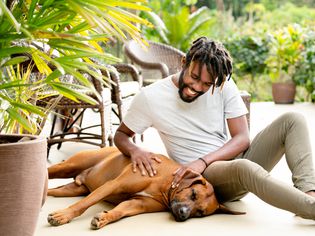 smiling man petting his dog in the backyard