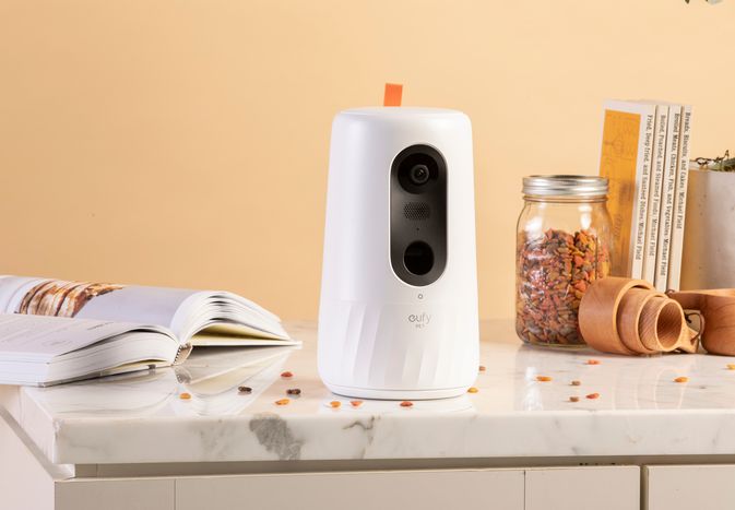 Eufy indoor pet camera displayed on a counter with books and a jar of kibble