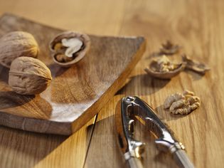 Walnut pieces and nutcracker on cutting board, close-up
